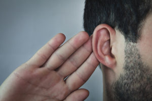 Man putting hand up to ear to hear