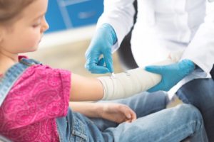 child having cast put on arm by a doctor