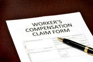 worker's compensation claim form and ball pen on top of a table